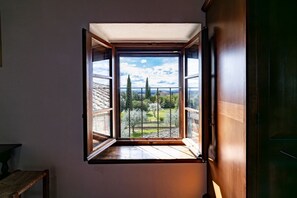 A room with a large window, a wooden door, and a small table. - Charming 160 square meters apartment, perfect for six people, located on the first floor of a recently renovated medieval convent (no elevator).The property is located in Monti, a hamlet of Gaiole in Chianti: the area is extremely quiet and surrounded by (Monti)