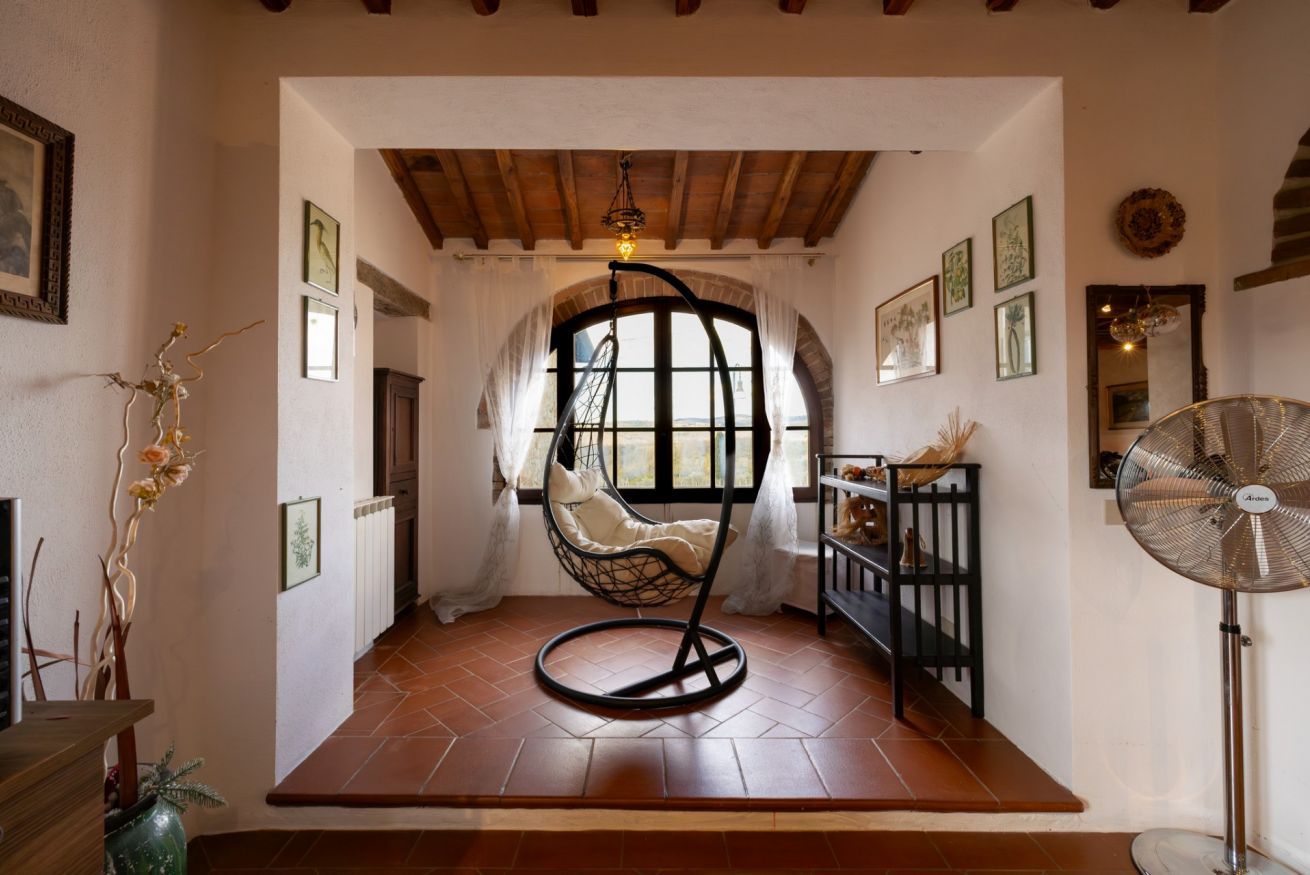 Habitació amb una cadira penjant, un ventilador i una vista per la finestra.