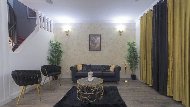 Ein Wohnzimmer mit einer Couch, zwei Sesseln, einem Couchtisch und einer Treppe.