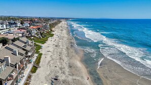 Un hotel frente al mar con una extensa playa, varios balcones y una vista despejada del océano.