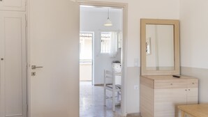 A room with a door, a mirror, a chair, a small table, and a light fixture. - BOHOTEL Eleonas Anex Apartments (Corfu)