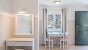 A room with a white desk, two chairs, a window with curtains, a green door, and a mirror above the desk. - BOHOTEL Eleonas Anex Apartments (Corfu)