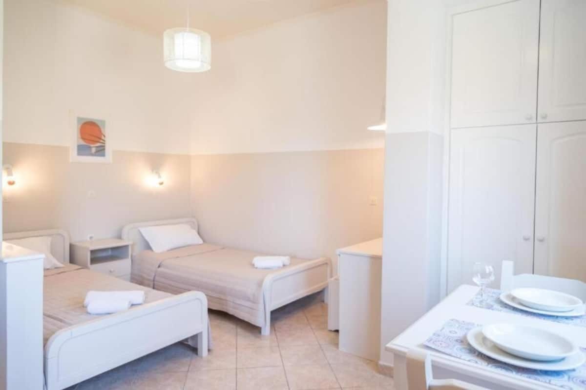 Una habitación con dos camas, una mesita con platos y un armario.