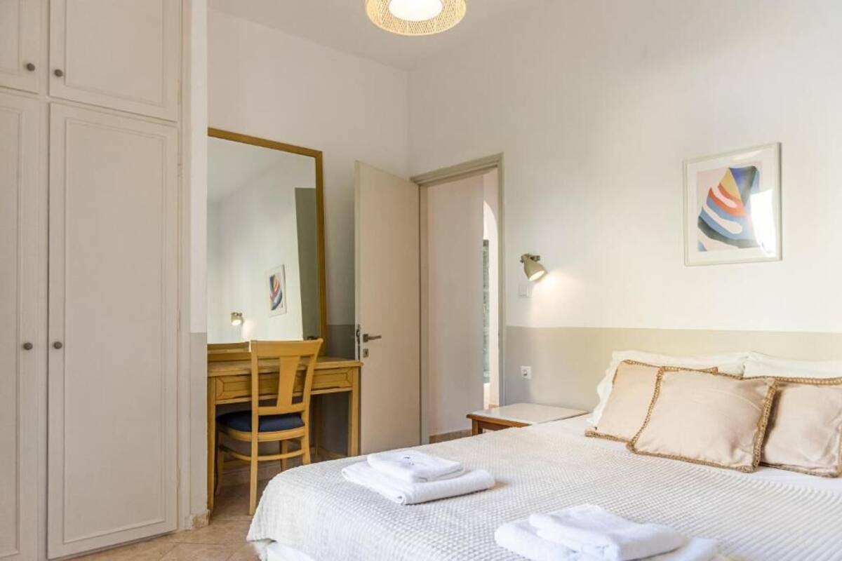 Un dormitorio con cama, escritorio, silla, espejo y una lámpara fijada a la pared.