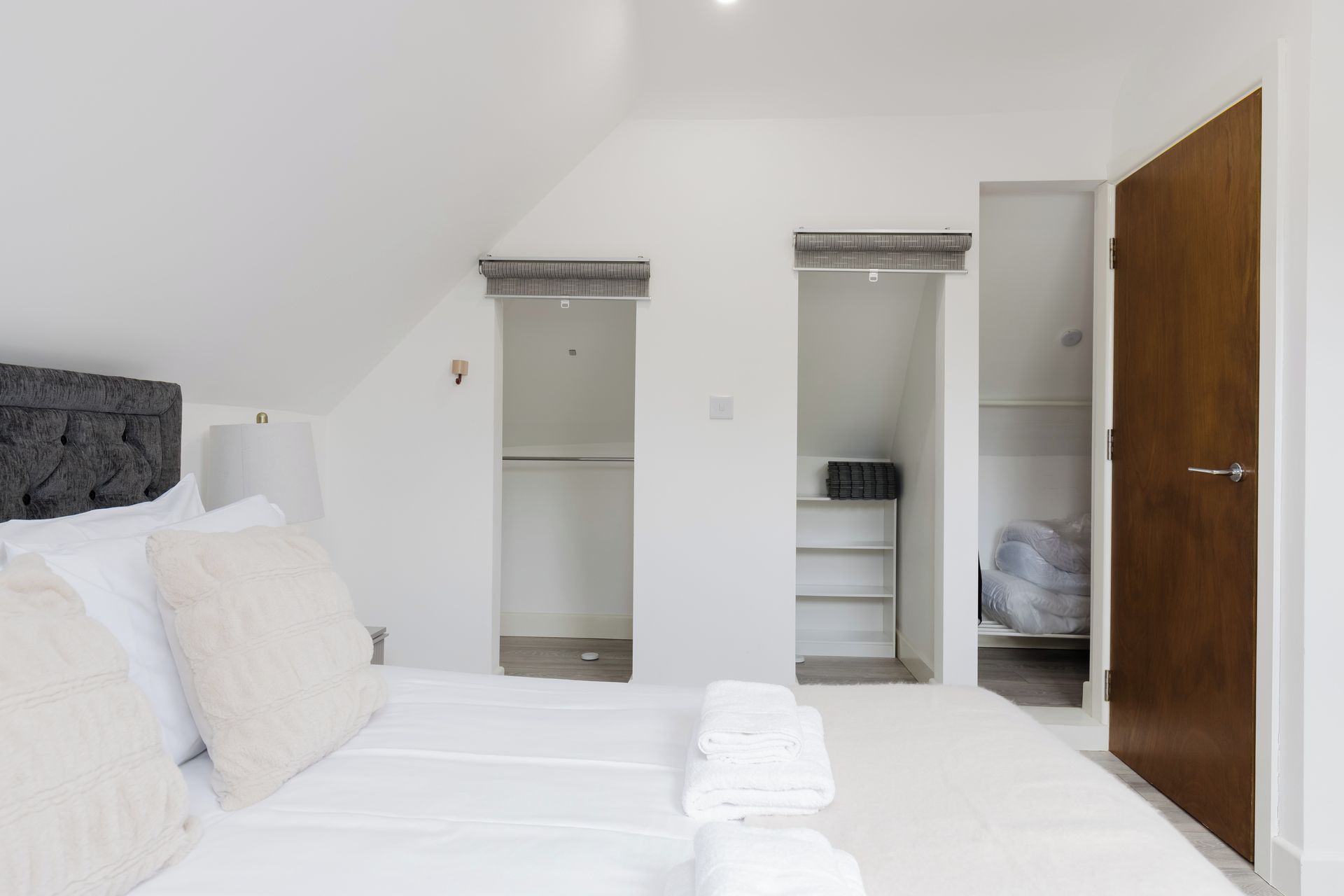 A bedroom with a bed, a wardrobe, and a bathroom with a shower.