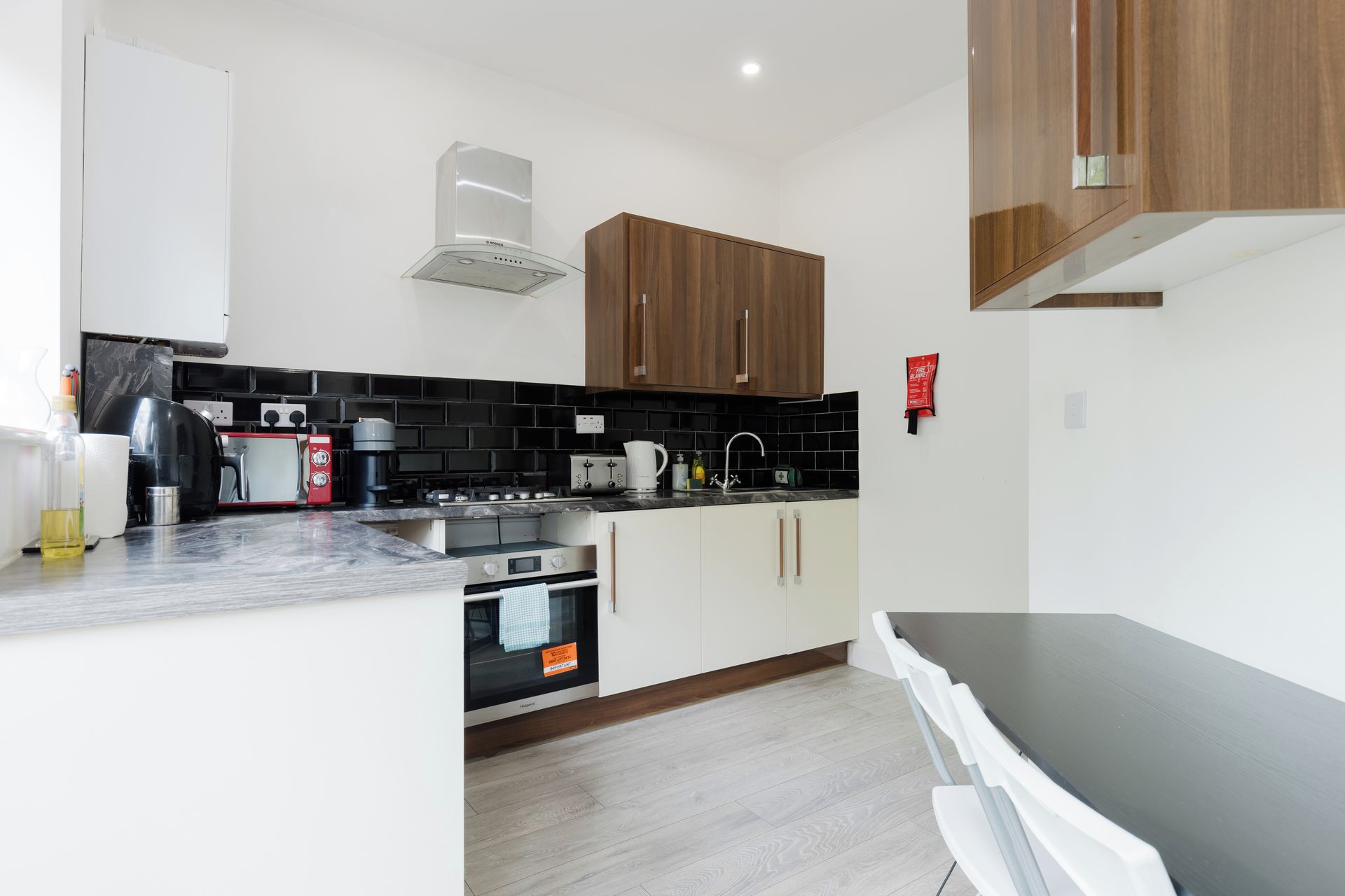 A modern kitchen with a stove, oven, and black tiled backsplash.
