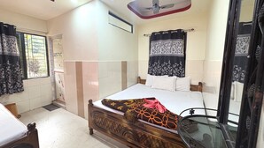 Ein Schlafzimmer mit Bett, Deckenventilator, Fenster mit Vorhängen und einer Tür.