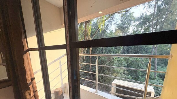 Ein Zimmer mit großem Fenster, Metallgeländer und Blick auf eine bewaldete Landschaft.