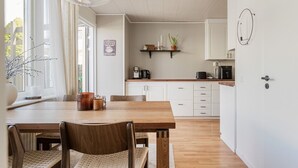 Et moderne køkken med hvide skabe, et træspisebord og en kaffemaskine.