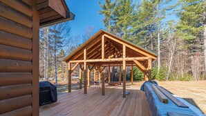 A wooden deck with a covered area, surrounded by trees. - Riverwood Chalet- Near Sunday River (Newry)