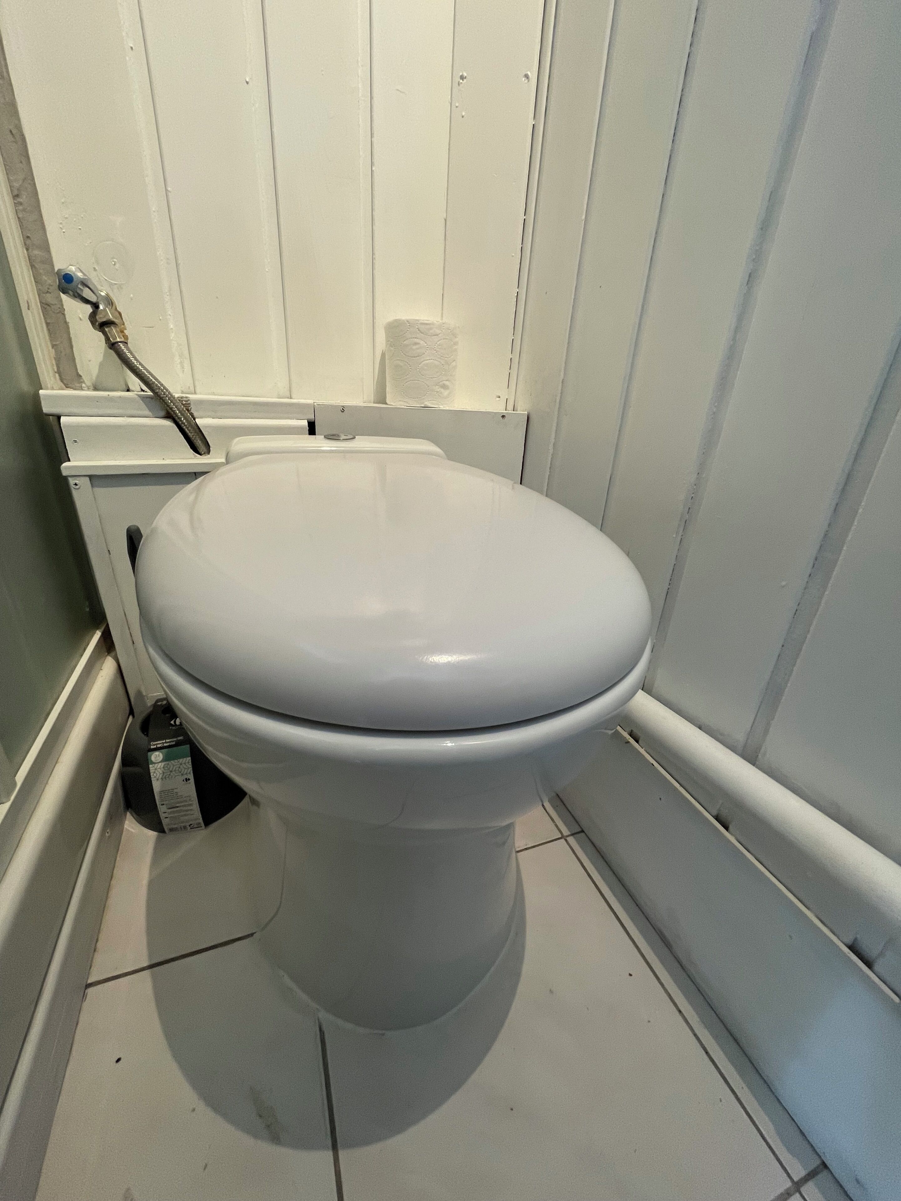A white toilet in a bathroom with white walls and a white floor.