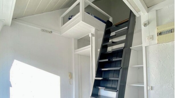 Una habitación con techo blanco, una escalera espiral negra y paredes blancas.
