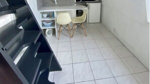 Una cocina compacta con estufa, dos sillas y una pequeña mesa de comedor.