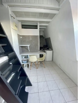 Une cuisine de taille réduite, équipée d’une cuisinière, de deux chaises et d’une petite table à manger.