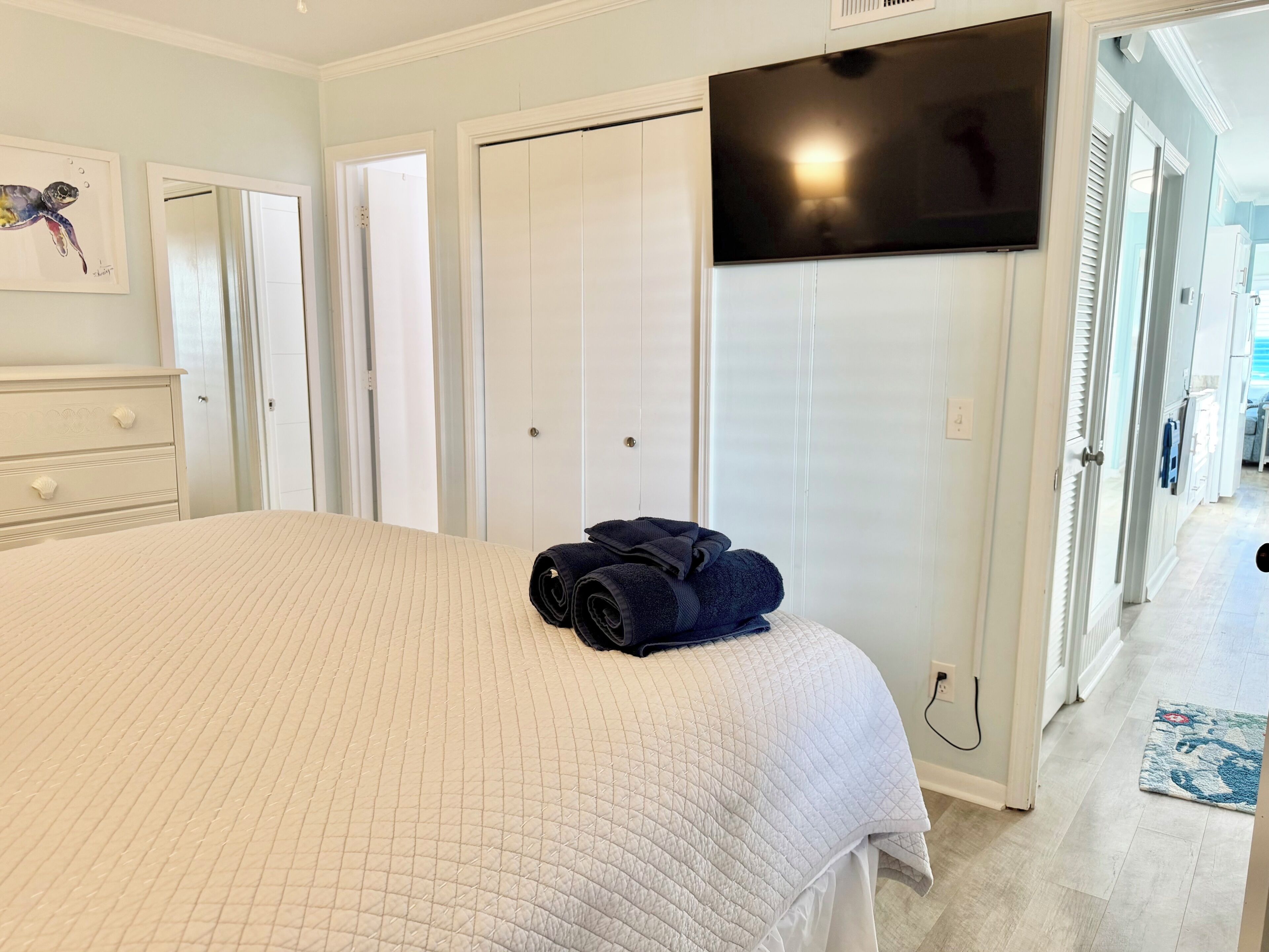 Une chambre à coucher avec un lit, un téléviseur fixé au mur et une armoire.