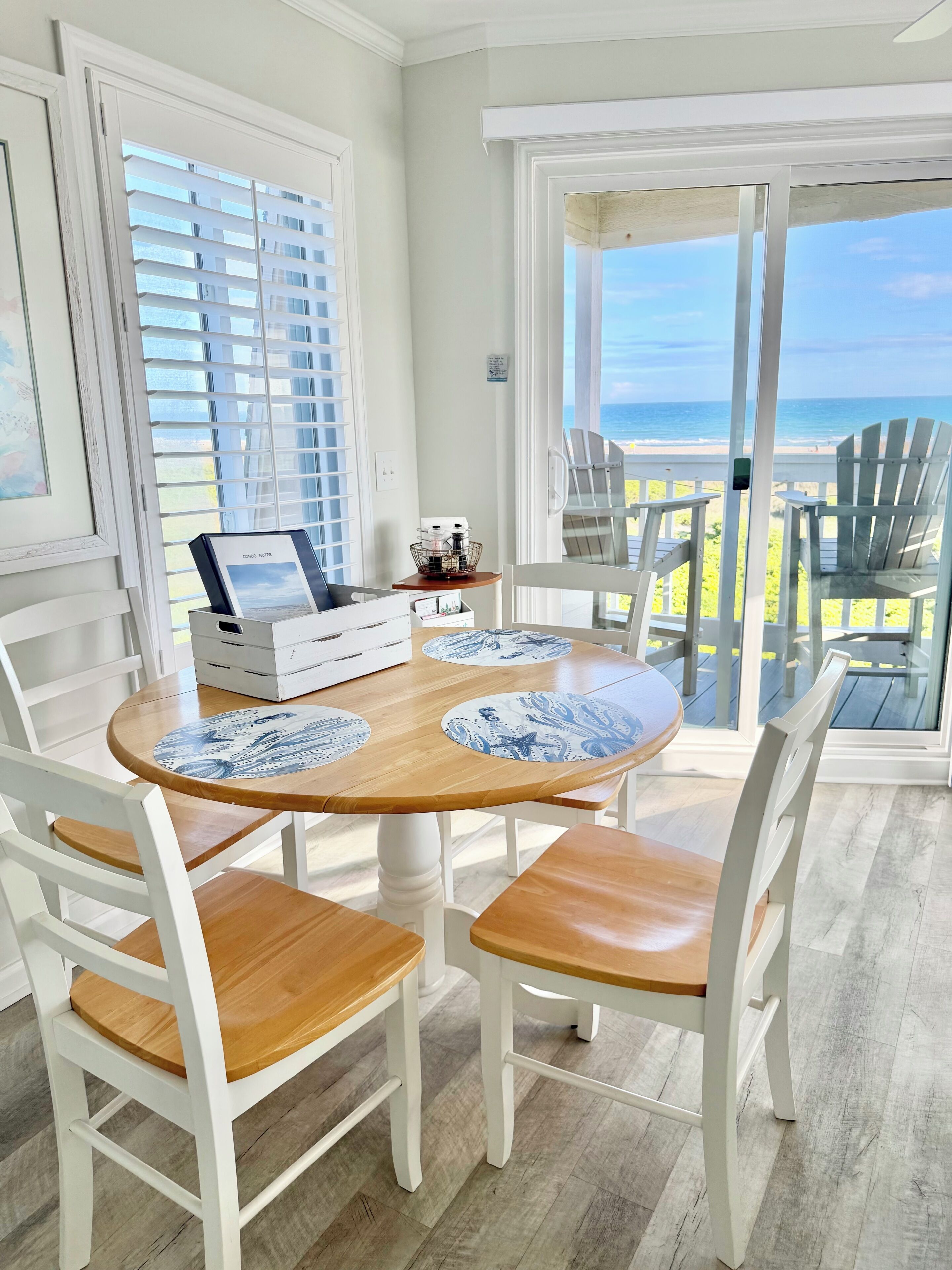 Un coin repas avec une table ronde, des chaises blanches et une vue sur la plage.