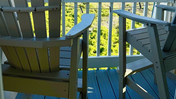 A wooden deck with two Adirondack chairs facing a beach view. - Seaside Retreat - oceanfront, pool sleeps 4, views, previous”Leg-a-Sea” (Atlantic Beach)