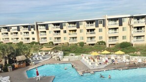 A hotel with a large swimming pool, multiple balconies, and outdoor seating areas. - Seaside Retreat - oceanfront, pool sleeps 4, views, previous”Leg-a-Sea” (Atlantic Beach)