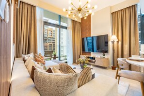 A modern living room with a sofa, TV, and dining area. - Near Meydan Racecourse, Minutes Car Drive to Downtown and Burj Khalifa (Dubai)