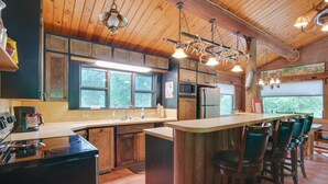 Una cocina con armarios de madera, una isla central con taburetes de bar, una estufa y un refrigerador.