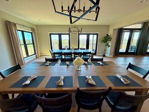 Ein Esszimmer mit großem Tisch, Stühlen und einer Kronleuchter.