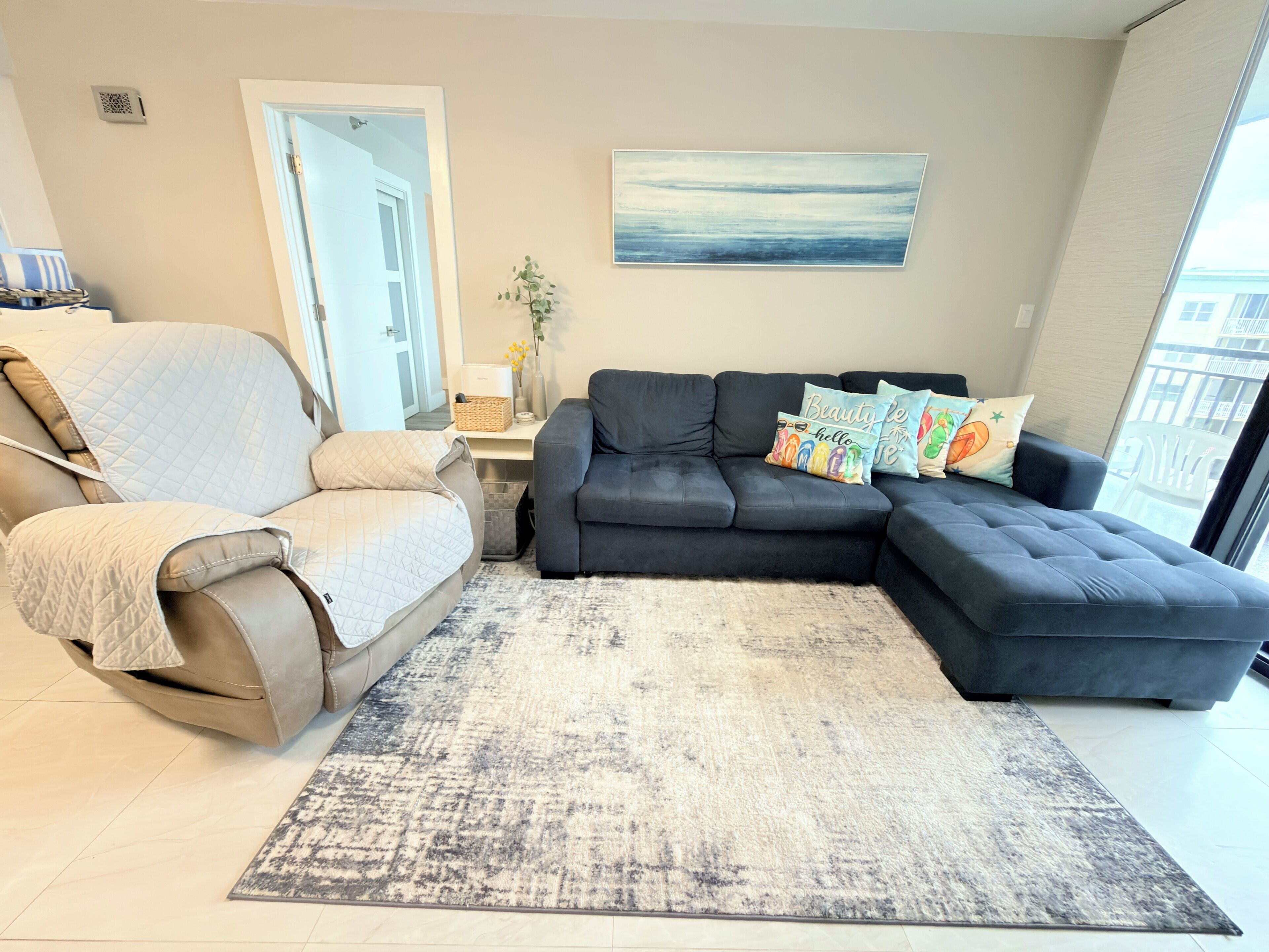 Ein Wohnzimmer mit einer Couch, einem Sessel, einem Teppich und einem Gemälde an der Wand.