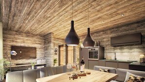 Una cocina moderna con techo de madera, un comedor con mesa de madera, y una zona de estar con sofás y sillones.