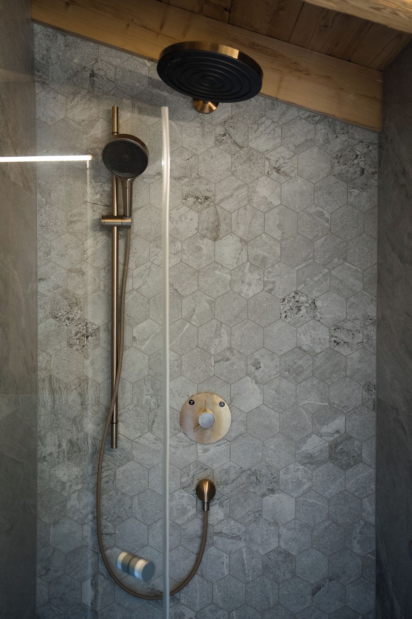 A shower with a glass enclosure, a handheld showerhead, and a wall-mounted control panel.