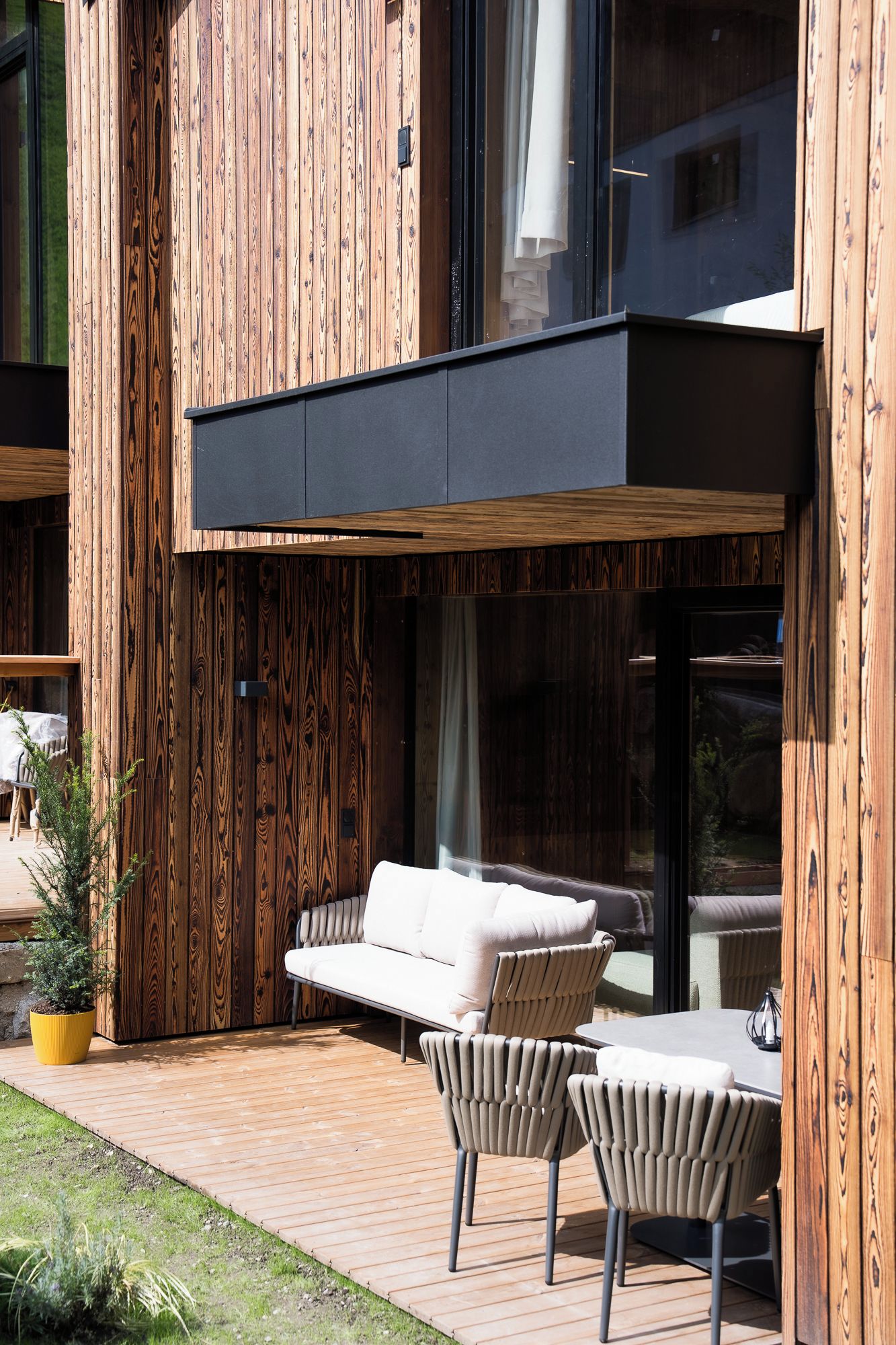 An outdoor seating area with a sofa and chairs, a small table, and a potted plant.