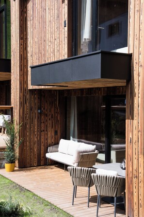 An outdoor seating area with a sofa and chairs, a small table, and a potted plant.