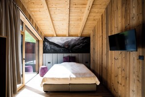 Un dormitorio con cama, televisión y un mural con vistas a la montaña.