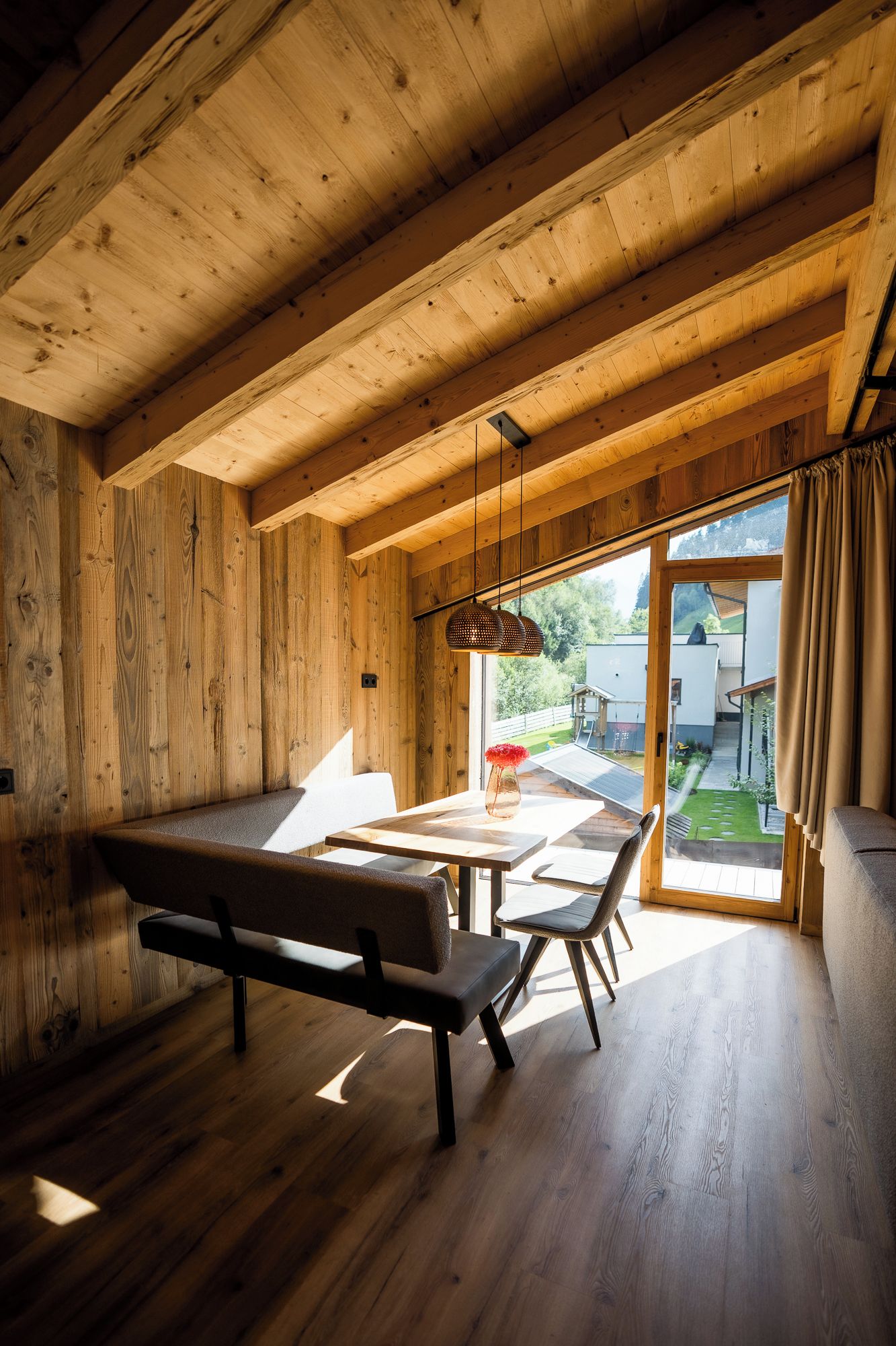 A wooden interior with a bench, table, and hanging light fixture.