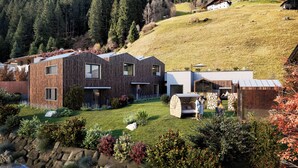 Un barrio residencial moderno con casas de madera, un césped cuidado y un risco boscoso al fondo.