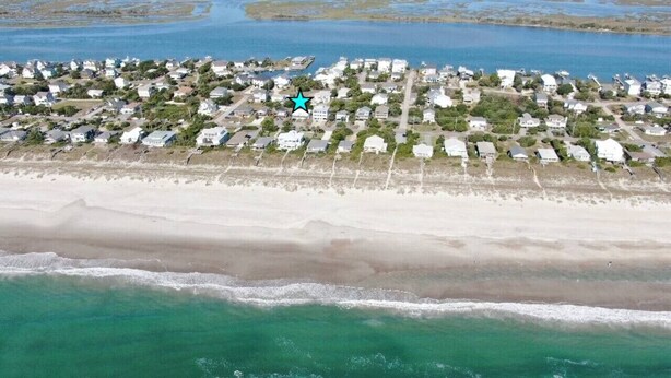 Vista aerea di una zona residenziale costiera con case, una spiaggia e una distesa d'acqua.