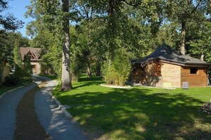A rustic cabin with a gravel path leading to it, surrounded by lush greenery and trees.
