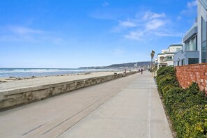 Une promenade en bord de mer, avec une plage, des bâtiments et un ciel dégagé.