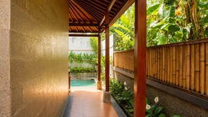 A covered outdoor area with a pool, surrounded by bamboo fencing and lush greenery. - Fortuna Romantic Villa Petulu by TVM (Ubud)