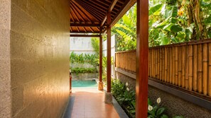 A covered outdoor area with a pool, surrounded by bamboo fencing and lush greenery. - Fortuna Romantic Villa Petulu by TVM (Ubud)
