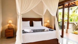 A bed with a canopy, two bedside lamps, and a view of a tropical garden. - Fortuna Romantic Villa Petulu by TVM (Ubud)