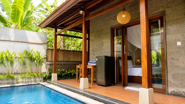 A poolside area with a wooden pergola, a refrigerator, and a bed with a canopy. - Fortuna Romantic Villa Petulu by TVM (Ubud)