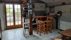 Een keuken met rieten dak, houten stoelen, een tafel en een ladder.