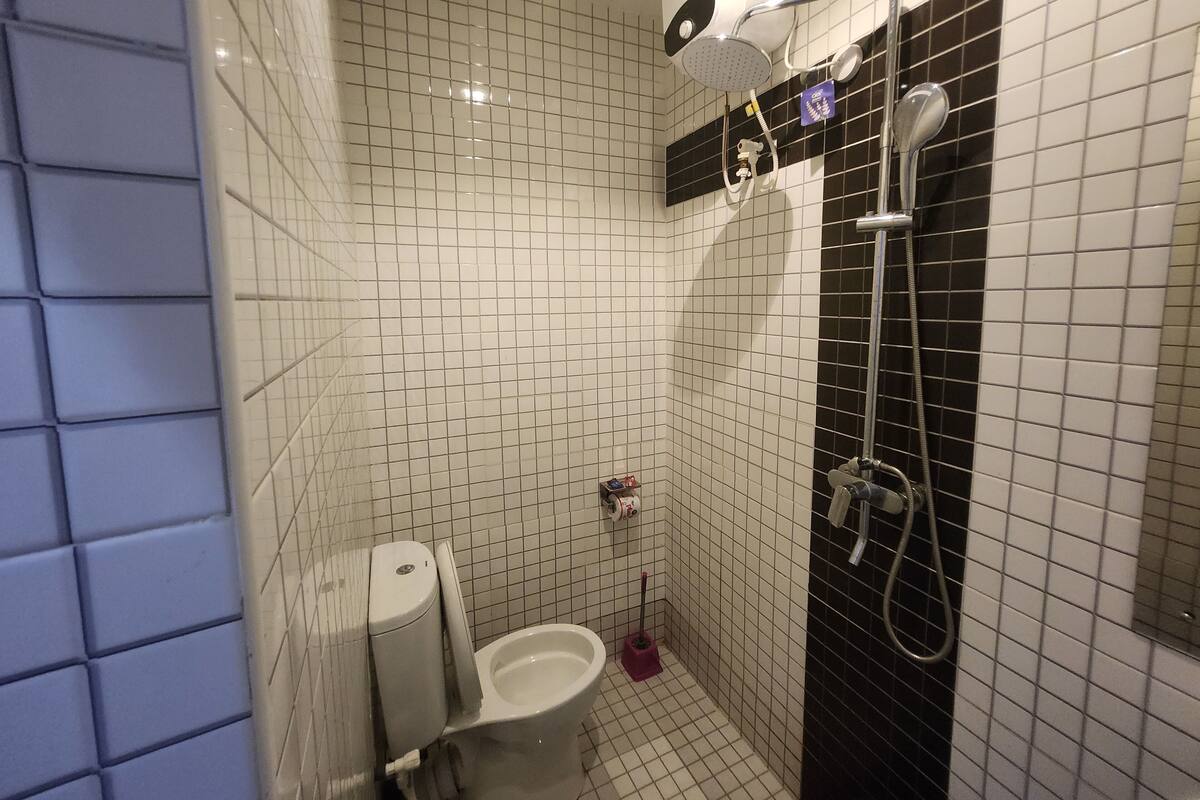 Ein Badezimmer mit Toilette, Dusche und einem Händetrockner.