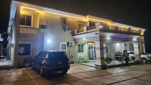 Un bâtiment à deux étages doté d’une entrée couverte, de plusieurs unités de climatisation et d’une voiture garée.
