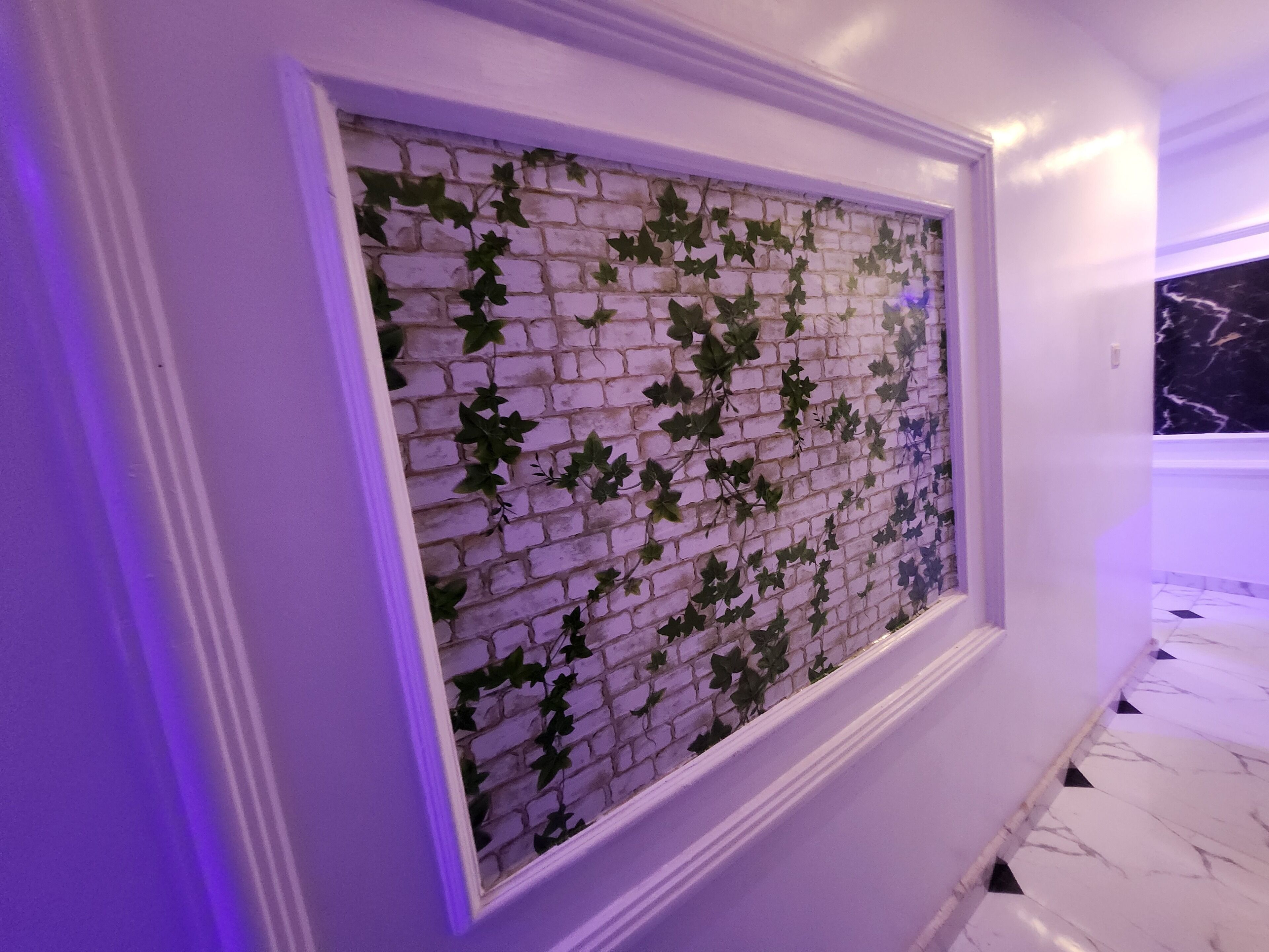 Een gang met een witte bakstenen muur en groene klimop.