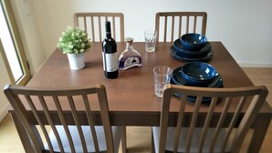 Un tavolo da pranzo con sedie, una bottiglia, un bicchiere, una piccola pianta e piatti impilati.