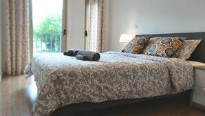 Una camera da letto con un letto, cuscini, un comodino e una finestra con tende.
