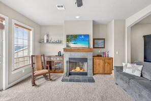 Ein Wohnzimmer mit Kamin, Fernseher, einer Holzkabine und Blick ins Freie.