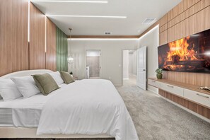 Ein modernes Schlafzimmer mit einem großen Bett, einem darüber montierten Fernseher und einem Holzschrank.
