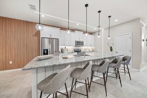 Una cucina moderna con isola centrale, elettrodomestici in acciaio inossidabile e sgabelli da bar.