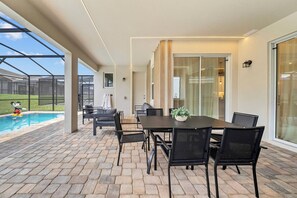 Ein überdachter Patio-Bereich mit Pool, Gartenmöbeln und einem Esstisch.